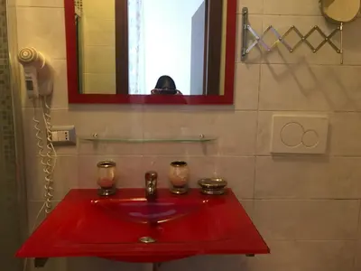 a red sink in a bathroom with a person taking a picture at La Casa di Elena in Rome
