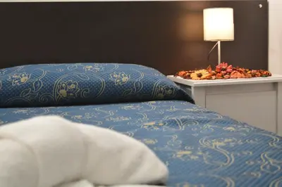 a bed with a pillow and a table with a lamp at Locanda Otello in Rome