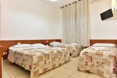 a hotel room with three beds and a tv at B&B Rome Terminal House in Rome