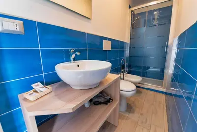 a bathroom with a sink and a toilet and blue tiles at Hotel Balilla in Rome