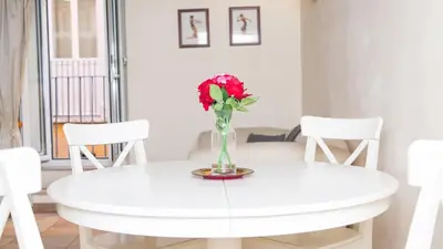 a white dining room table with a vase of flowers on it at Rental in Rome Falegnami in Rome