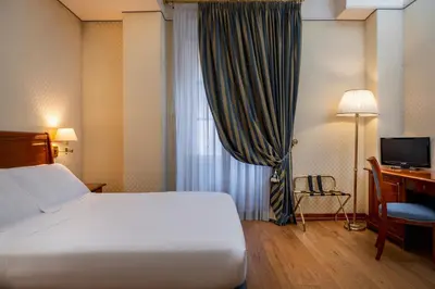 a hotel room with a bed and a desk and a window at Hotel Oceania in Rome