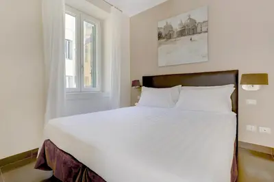 a white bed in a room with a window at Colosseo Gardens - My Extra Home in Rome
