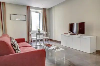 a living room with a red couch and a tv at Colosseo Gardens - My Extra Home in Rome