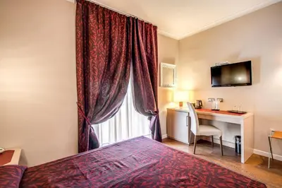a hotel room with a bed and a desk and a window at Boutique Rome Inn in Rome