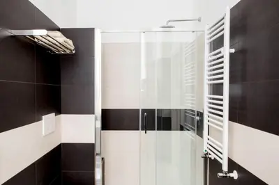 a glass shower in a bathroom with black and white tiles at Four Elements in Rome