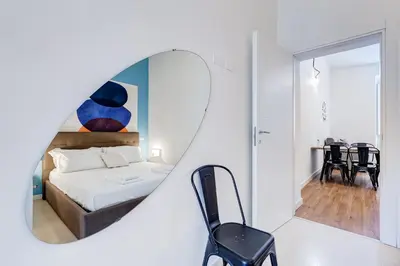 a bedroom with a bed with a mirror and a chair at BMGA l Central Holiday House 2Bdr near Vatican in Rome