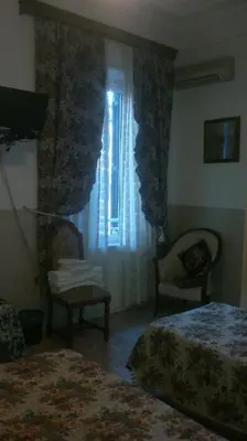 a bedroom with two beds and a window with curtains at Hotel Stadler 2 in Rome