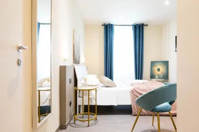 a small bedroom with a bed and a blue chair at Cesar Vatican Rooms in Rome