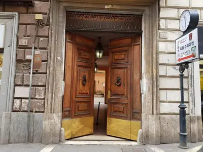a large wooden door on a building with a clock at APPARTAMENTO SIMONE DUE in Rome