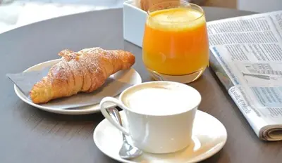 a table with a cup of coffee and a croissant and orange juice at Locanda Navona in Rome