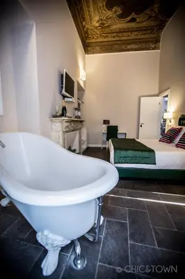 a bathroom with a bath tub and a bed at Chic & Town Luxury Rooms Piazza di Spagna in Rome