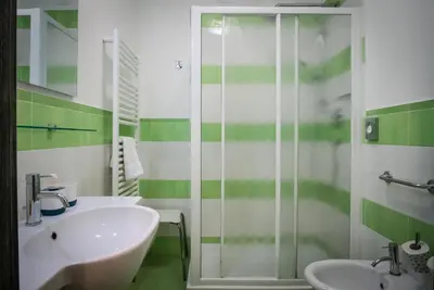 a green and white bathroom with a sink and a shower at Mocenigo Vatican Suites in Rome