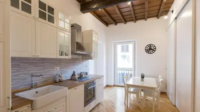 a kitchen with white cabinets and a table and a sink at Rental in Rome Trastevere Atmosphere in Rome