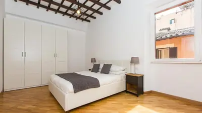 a white bedroom with a bed and a window at Rental in Rome Trastevere Atmosphere in Rome