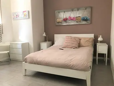 a bedroom with a white bed with a pink pillow at CRIS - close to VATICAN - Centre&StadiumArea in Rome