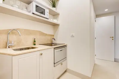 a kitchen with white cabinets and a sink and a microwave at Trevi Chic House in Rome