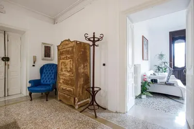 a room with a blue chair and a wooden cabinet at Flat Six in Rome