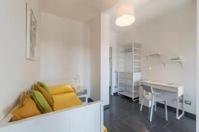 a room with a desk and a bed with yellow pillows at Nomentana White Apartments in Rome