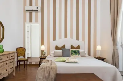 a bedroom with a large white bed with striped walls at New! Spanish Step Design Apartment in Rome