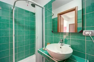 a green bathroom with a sink and a mirror at MF Hotel in Rome