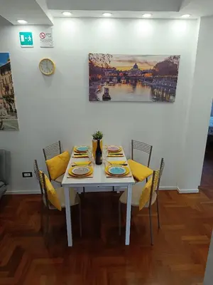 a dining room table with yellow cushions and a painting at Casa Vacanze Mafalda - Roma Stazione Trastevere in Rome