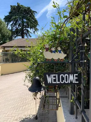 a welcome sign in a garden with a bell at A casa di Elly in Rome