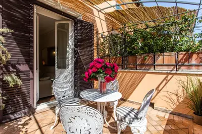 a patio with two chairs and a table with flowers at Frattina Apartments in Rome