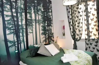 a bedroom with a green bed with trees on the wall at giolitti central room in Rome