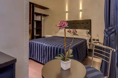 a room with a bed and a table with a flower on it at Residenza Dorò- 24x7 Check-in in Rome