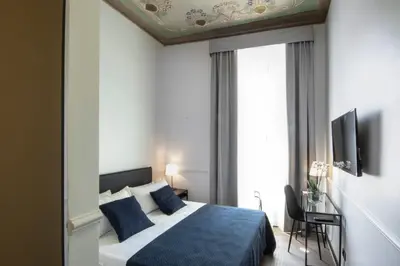 a bedroom with a blue bed and a window at Gemini Suites Navona in Rome