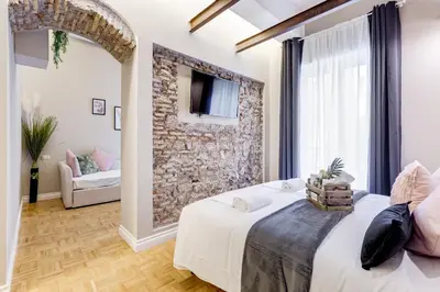 a bedroom with a bed and a stone wall at Tankara Suite in Rome