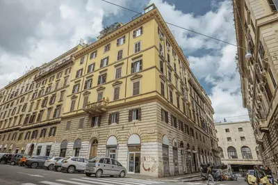 a large yellow building with cars parked in front of it at Walker Rooms in Rome