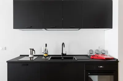 a kitchen with black cabinets and a sink at A World Aparts - 104 Frattina in Rome