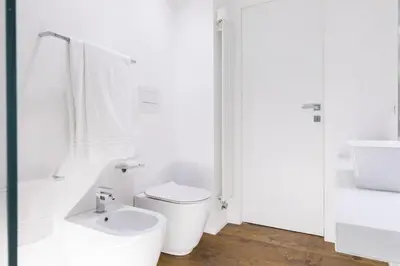 a white bathroom with a toilet and a sink at A World Aparts - 104 Frattina in Rome