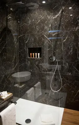 a bathroom with a shower with a black marble wall at Unicum Roma Suites in Rome