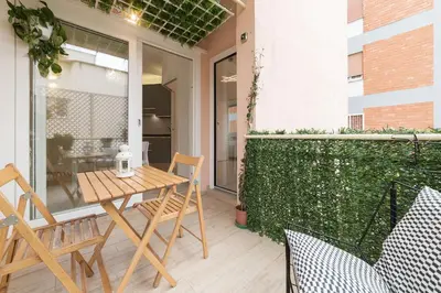 a patio with a table and chairs and a green hedge at Appartamenti Clivo di Monte del Gallo in Rome