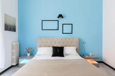 a blue bedroom with a large bed with white pillows at A World Aparts - 23 Artisti in Rome