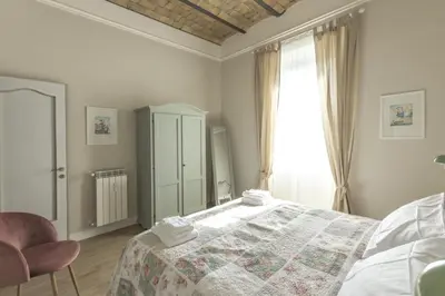 a white bedroom with a bed and a window at Casa di Ele in Rome