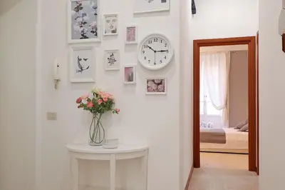 a vase of flowers on a table with a clock on a wall at Olafo’s house in Rome
