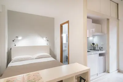 a white bedroom with a bed and a kitchen at Magenta Collection Terrione 17 in Rome