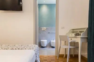a bedroom with a bed and a desk and a bathroom at Dulcis In Vatican b&b in Rome