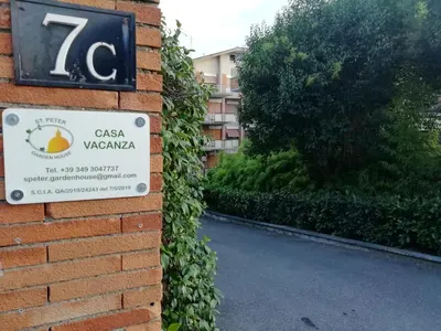 a sign on a brick wall next to a street at St. Peter Garden House in Rome