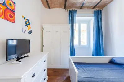 a bedroom with a tv on a white dresser with a blue curtain at Saint Peters Luxury 3 Bedrooms Apartment in Rome