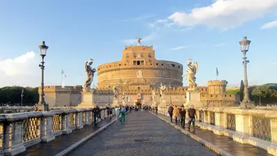 people walking across a bridge in front of a building at Rome Luxury House - The House in Rome