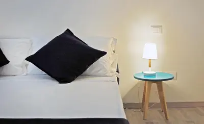 a bed with a black pillow and a table with a lamp at Pompeo Magno White Luxury Apartment in Rome