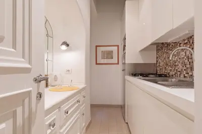 a white kitchen with a sink and a counter at Rome As You Feel - Cancelli Apartment in Rome