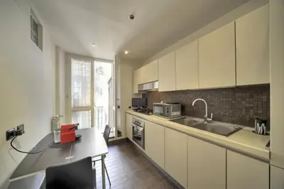 a kitchen with white cabinets and a table and a sink at ROME LUXURY HOUSE - THE SUITE in Rome