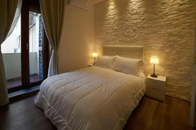 a bedroom with a white bed with a brick wall at Malenki in Rome