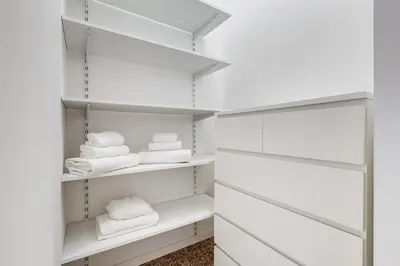 a walk in closet with white shelves and towels at BDC - Termini Sun Apartment in Rome